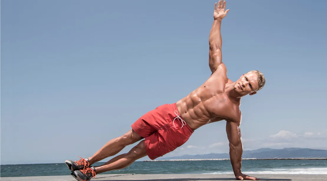 Person doing bodyweight beach workout on sand near the ocean